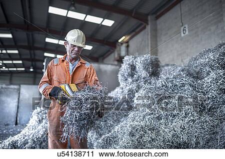 Stock Image - Worker testing titanium swarf in titanium recycling plant. Fotosearch