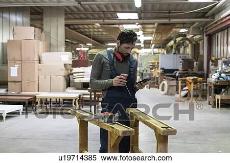 Worker using smartphone during coffee break in factory View Large Photo Image Stock Photography - Worker using smartphone during coffee break in factory. Fotosearch
