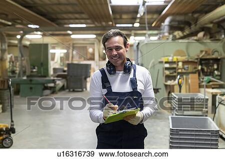 Stock Photo - Worker with clipboard in factory. Fotosearch