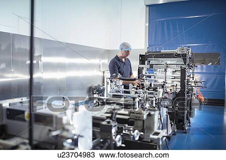 Worker with food packaging machine in print factory View Large Photo Image Stock Image - Worker with food packaging machine in print factory. Fotosearch