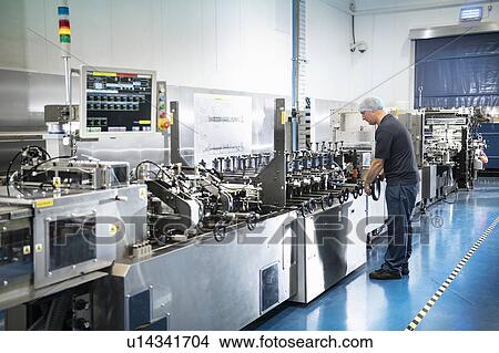 Worker with food packaging printing machine in print factory View Large Photo Image Picture - Worker with food packaging printing machine in print factory. Fotosearch