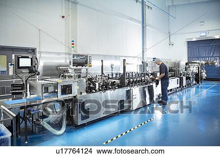 Picture - Worker with food packaging printing machine in print factory. Fotosearch