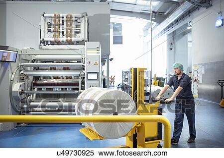 Stock Photography - Worker with food packaging printing machine in print factory. Fotosearch