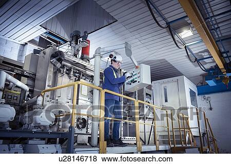 Stock Photo - Worker with furnace equipment in titanium recycling plant. Fotosearch