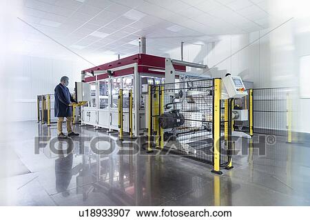 Stock Photo - Worker with laser printing machine in print factory. Fotosearch