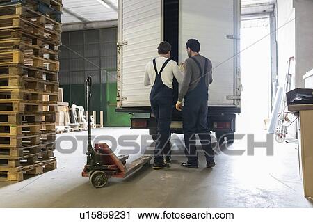 Workers closing door of truck in factory View Large Photo Image Stock Image - Workers closing door of truck in factory. Fotosearch