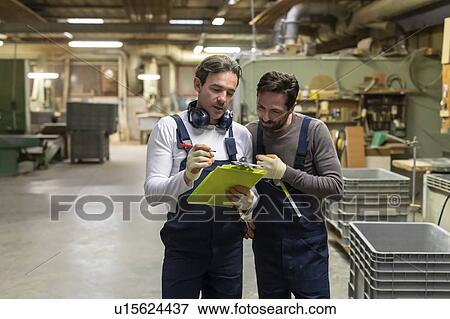 Stock Photo - Workers discussing work in factory. Fotosearch