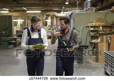Workers discussing work in factory View Large Photo Image Stock Photograph - Workers discussing work in factory. Fotosearch