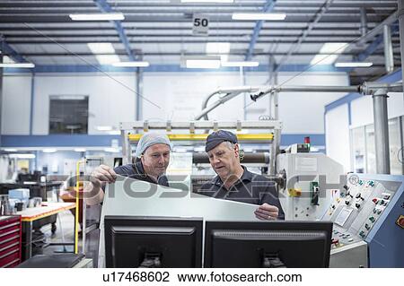 Stock Image - Workers inspecting food packaging in food factory. Fotosearch