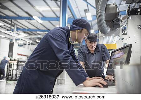 Stock Photo - Workers inspecting print output in print factory. Fotosearch