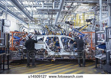 Stock Photo - Workers loading car body spot welding machine with robots in car factory. Fotosearch