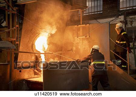 Stock Photo - Workers pouring liquid titanium alloy from furnace in titanium recycling plant. Fotosearch