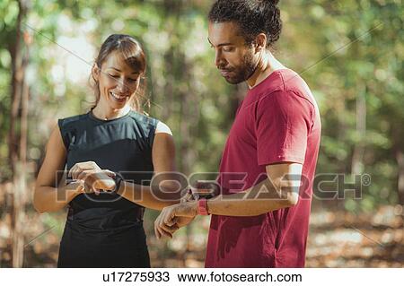 Young couple looking at their smart watches after training View Large Photo Image Stock Image - Young couple looking at their smart watches after training. Fotosearch