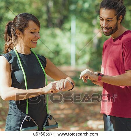 Young couple looking at their smart watches after training View Large Photo Image Stock Image - Young couple looking at their smart watches after training. Fotosearch