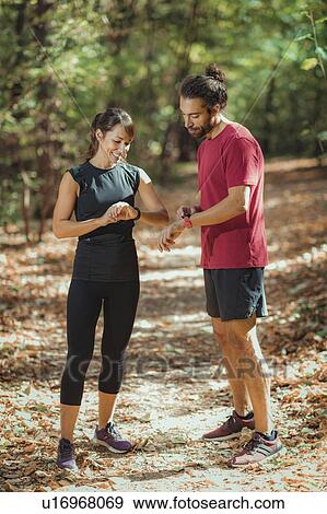 Young couple looking at their smart watches after training View Large Photo Image Stock Photo - Young couple looking at their smart watches after training. Fotosearch