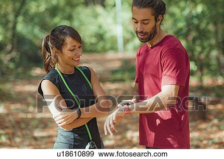 Young couple looking at their smart watches after training View Large Photo Image Stock Photo - Young couple looking at their smart watches after training. Fotosearch
