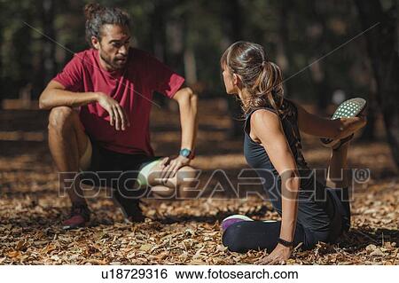Stock Photograph - Young couple stretching after training in the park. Fotosearch