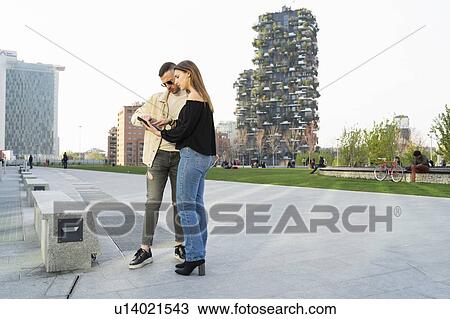 Stock Image - Young couple using digital tablet in city, Milano, Lombardia, Italy. Fotosearch