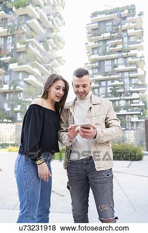 Young couple using smartphone in city, Milano, Lombardia, Italy View Large Photo Image Stock Photo - Young couple using smartphone in city, Milano, Lombardia, Italy. Fotosearch