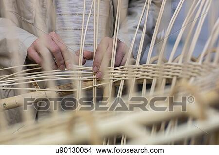 Picture - Young female basket maker weaving in workshop, mid section. Fotosearch