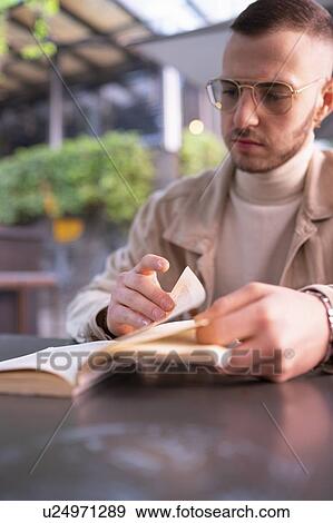 Young man reading book at cafe, Milano, Lombardia, Italy View Large Photo Image Stock Photo - Young man reading book at cafe, Milano, Lombardia, Italy. Fotosearch