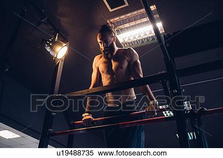 Young man training in gym, doing push ups on exercise bar View Large Photo Image Stock Photography - Young man training in gym, doing push ups on exercise bar. Fotosearch