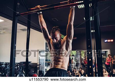 Young man training in gym, swinging on exercise bar View Large Photo Image Stock Image - Young man training in gym, swinging on exercise bar. Fotosearch