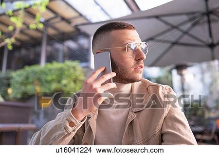 Young man using smartphone at cafe, Milano, Lombardia, Italy View Large Photo Image Picture - Young man using smartphone at cafe, Milano, Lombardia, Italy. Fotosearch