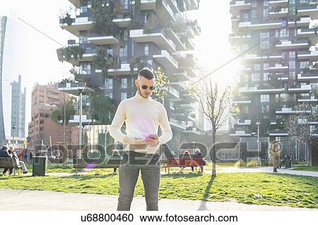 Young man using smartphone in city, Milano, Lombardia, Italy View Large Photo Image Stock Image - Young man using smartphone in city, Milano, Lombardia, Italy. Fotosearch