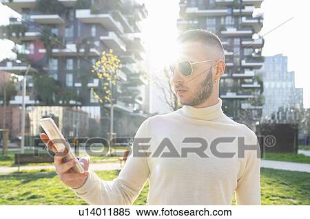 Young man using smartphone in city, Milano, Lombardia, Italy View Large Photo Image Stock Photography - Young man using smartphone in city, Milano, Lombardia, Italy. Fotosearch