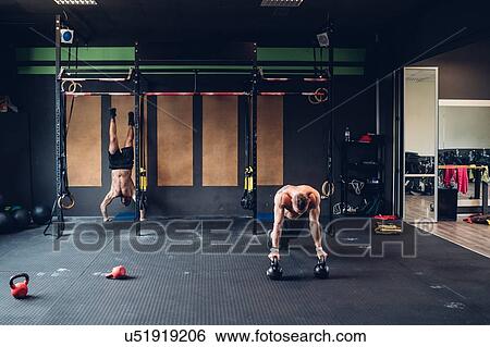 Young men training in gym, doing push ups and handstand View Large Photo Image Stock Photograph - Young men training in gym, doing push ups and handstand. Fotosearch