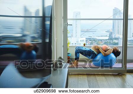 Young pregnant woman on apartment balcony lying back on exercise ball View Large Photo Image Stock Photo - Young pregnant woman on apartment balcony lying back on exercise ball. Fotosearch