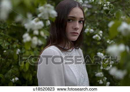 Stock Image - Young woman among white blossoms. Fotosearch