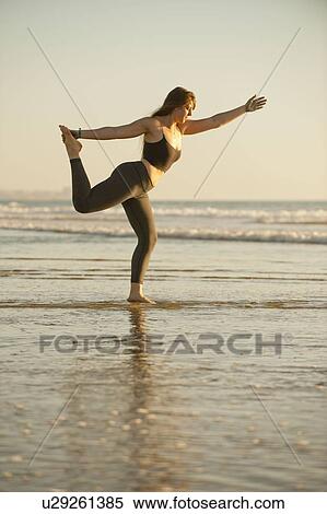 Stock Photography - Young woman doing yoga on beach. Fotosearch