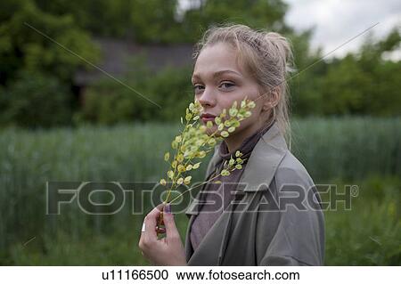 Stock Image - Young woman holding green branches. Fotosearch
