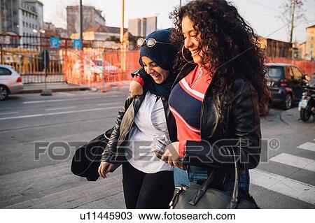 Young woman in hijab and best friend walking and talking in city View Large Photo Image Stock Image - Young woman in hijab and best friend walking and talking in city. Fotosearch