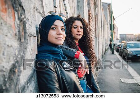 Young woman in hijab and best friend leaning against wall on city sidewalk View Large Photo Image Stock Image - Young woman in hijab and best friend leaning against wall on city sidewalk. Fotosearch