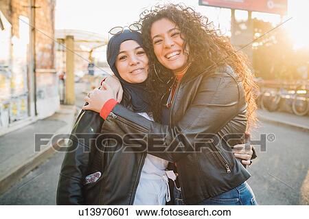 Young woman in hijab and best friend hugging each other in city, portrait View Large Photo Image Stock Image - Young woman in hijab and best friend hugging each other in city, portrait. Fotosearch