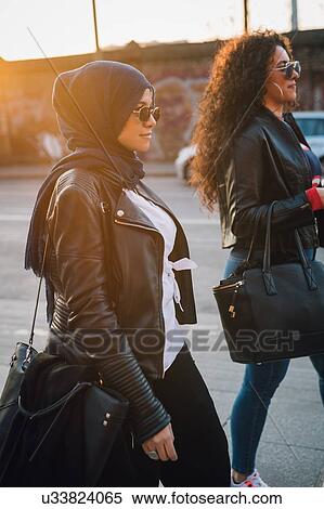 Stock Photography - Young woman in hijab and best friend strolling in city. Fotosearch