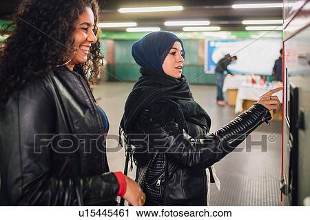 Young woman in hijab and friend buying tickets in subway station View Large Photo Image Stock Image - Young woman in hijab and friend buying tickets in subway station. Fotosearch