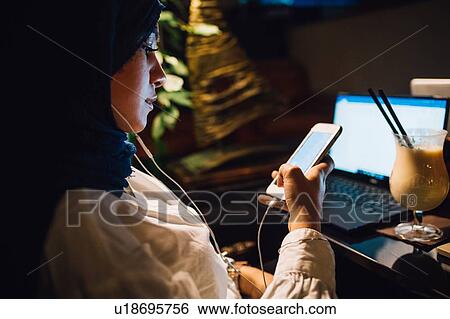 Young woman in hijab selecting music on smartphone in cafe View Large Photo Image Stock Photograph - Young woman in hijab selecting music on smartphone in cafe. Fotosearch