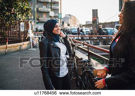 Young woman in hijab talking to friend in city View Large Photo Image Stock Photograph - Young woman in hijab talking to friend in city. Fotosearch