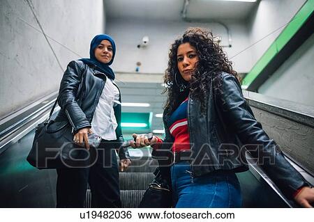 Young woman in hijab with friend moving up subway escalator View Large Photo Image Stock Photograph - Young woman in hijab with friend moving up subway escalator. Fotosearch