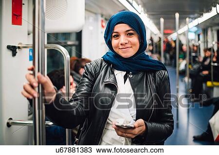 Young woman in hijab with smartphone on subway train, portrait View Large Photo Image Stock Image - Young woman in hijab with smartphone on subway train, portrait. Fotosearch