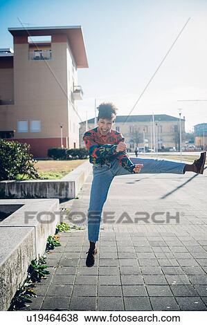 Young woman jumping and kicking leg on urban sidewalk, full length portrait View Large Photo Image Stock Photo - Young woman jumping and kicking leg on urban sidewalk, full length portrait. Fotosearch