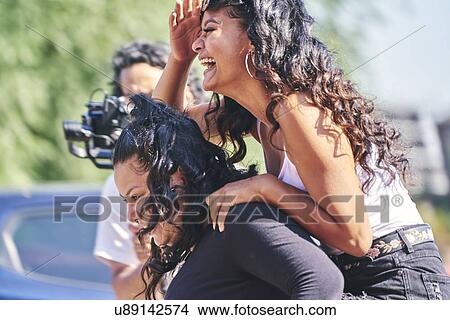 Young woman laughing while getting piggy back from teenage sister, side view View Large Photo Image Picture - Young woman laughing while getting piggy back from teenage sister, side view. Fotosearch