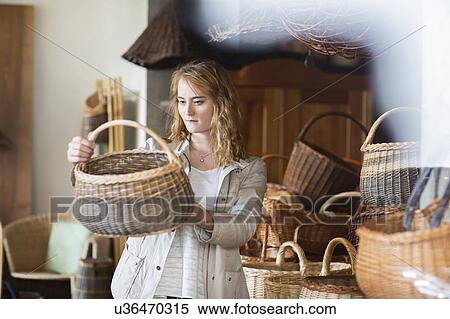 Young woman looking at wickerwork basket in shop View Large Photo Image Stock Photography - Young woman looking at wickerwork basket in shop. Fotosearch