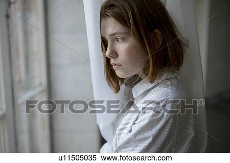 Stock Photography - Young woman looking out of window. Fotosearch