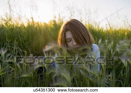 Stock Image - Young woman lying in wheat field. Fotosearch