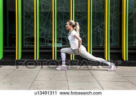 Stock Image - Young woman practicing yoga pose on city sidewalk, full length. Fotosearch